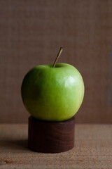 Ripe granny smith apple on wooden dowel.