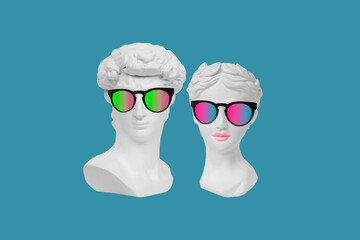 Two antique statue's heads in stylish sunglasses isolated on blue color background. Man and woman....