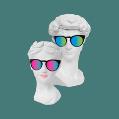 Antique statue's heads David and Aphrodite in sunglasses on green color background. Man and woman....