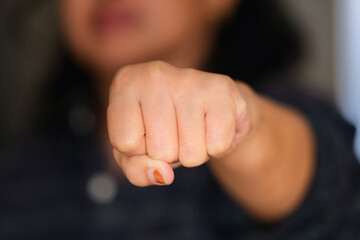 Close up of a woman's fist against a blurry face background