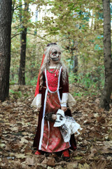 Girl child posing in the forest in a medieval dress in the image of a dead princess. Girl holding a doll