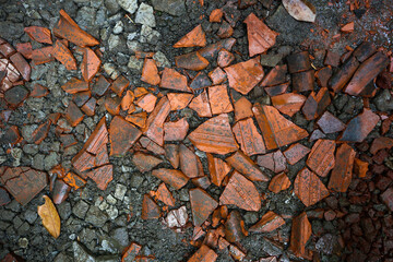 Tile fragments scattered on the ground mixed with dust and soil. Scattered tile fragments Background. Broken scattered rooftile.