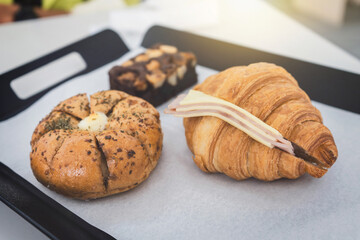 Korean Cream Cheese Garlic Bread, Ham Cheese Croissant and Chocolate Brownies on serving tray in a cafe dessert bakery or coffee shop.