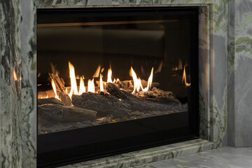 Burning gas fireplace built into marble