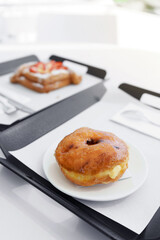 Donuts stuffed with Vanilla Custard Cream on a white plate in a serving tray in a cafe bakery.