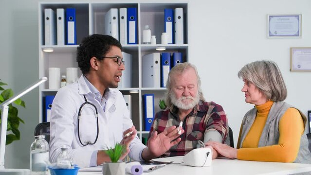 medical examination, a black doctor measures the pressure of an elderly man with his wife using modern devices in medical cabinet
