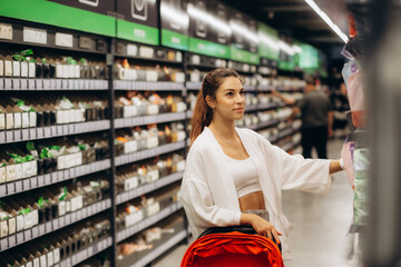 Woman buys diapers for child at the supermarket, portrait of young mother in shop mall.