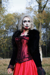 A woman in the form of a vampire or a witch in a corset and a long red skirt. Blood trickles down...