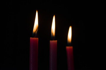 Closeup stock photo of three candles arranged in size order lighten up in dark room and focus on left candle horizontal photo