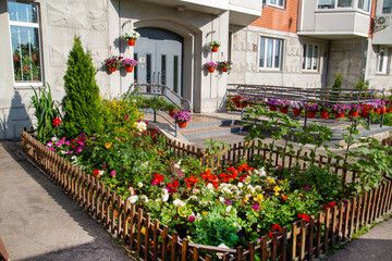 Flowerbeds of bright flowers and various plants in front of the entrance of a residential building. Agriculture Landscaping landscaping of cities.