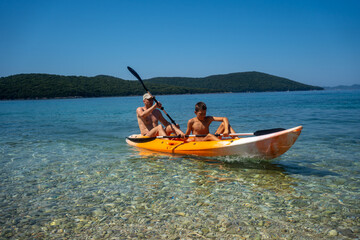father and son are kayaking on the beautiful sea