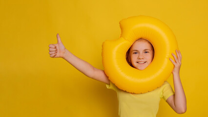 funny girl emoji face in inflatable ring with thumb up gesture hand over yellow background