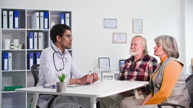 medical consultation, an elderly couple consults about state of health of a black doctor in office