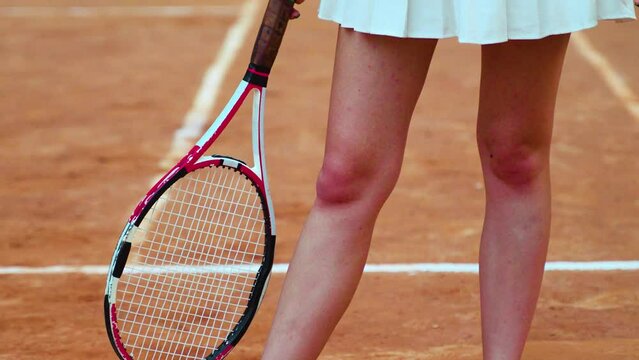 body of a woman tennis player wearing a white skirt and holding a racket