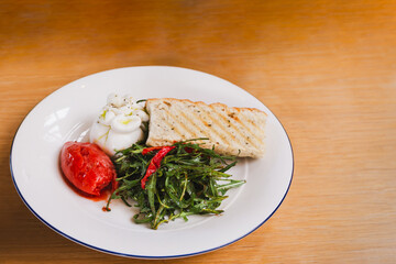 Rocket salad with Italian burrata cheese and tomato in white plate.