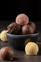 Close up of colorful chocolates on dark wooden table black background, selective focus, vertical, with copy space