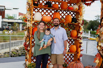 Happy Halloween and Thanksgiving - a smiling family and a little daughter on the background of orange pumpkins on holiday