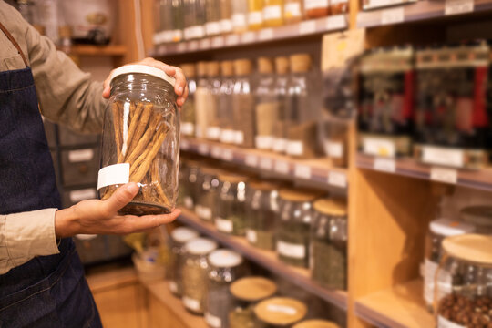 Crop male seller putting jars with assorted products on shelf
