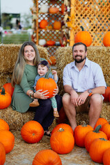 Happy Halloween and Thanksgiving - smiling mom and little daughter on the background of orange pumpkins on holiday