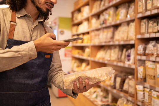 Crop black seller scanning code food in grocery store