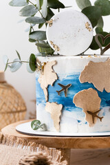 Birthday cake decorated with golden world map and flying airplane silhouettes on the white background. Traveling around the world concept. Birthday present for a traveller