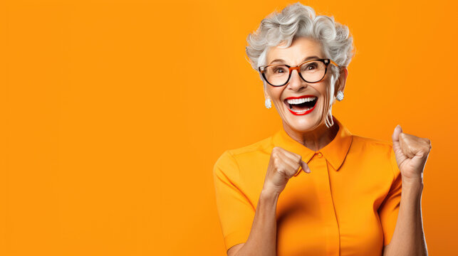 An elderly woman exited and shocked hands up against an orange background.