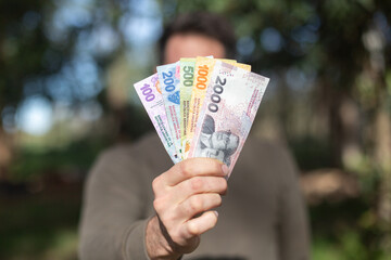 a handful of 100, 200, 500, 1000 and 2000 argentinean pesos banknotes.