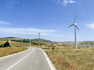 country road with wind turbines on the sides