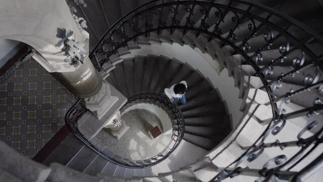 Woman go up the spiral stairs in old luxury building, slow motion