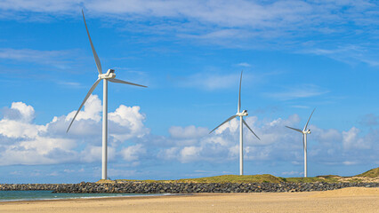 Windräder stehen an der Küste in den Dünen und erzeugen Energie durch Wind
