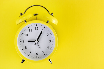 Yellow alarm clock on a colored yellow background. Monochrome. Minimalism. Concept of time, planning. Copy space.
