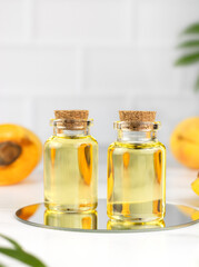 Apricot oil and fresh apricots in a transparent bottle on white bacjground. Natural cosmetic. Copy space.