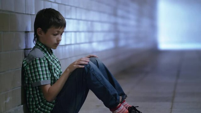 Lonely Boy with Bruised Eye Sitting Alone on the Underground Passage Floor, Feeling Helpless and Directionless