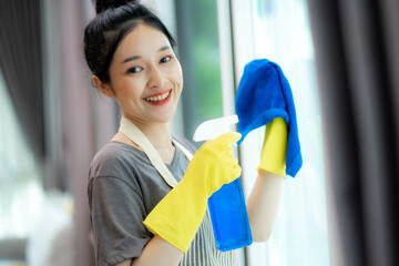 young woman cleaner in yellow protectibe rubber gloves cleaning window with spray and rag. Cleaning...