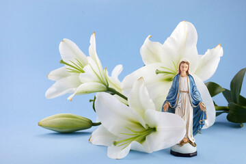 Assumption of Mary day. Virgin Mary figurine with lily flowers. - obrazy, fototapety, plakaty