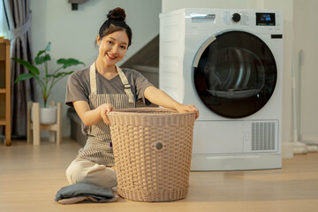 Beautiful young woman is smiling while doing laundry at home. Young woman near washing machine at home, Laundry day.