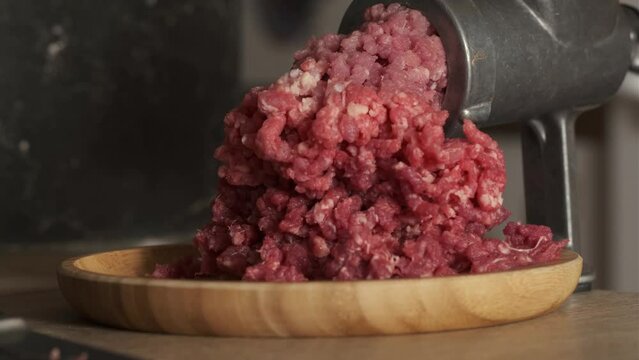 Close up of mincing beef meat with old manual meat grinder. Cooking meat for hamburger patties. Black concrete background