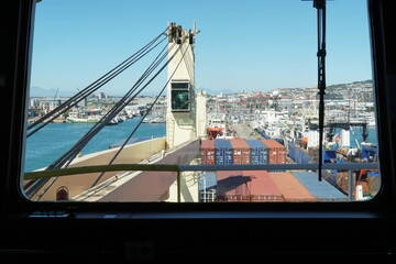 Direct view on cabin of ship crane behind steel greased wire of loaded container vessel moored in ...