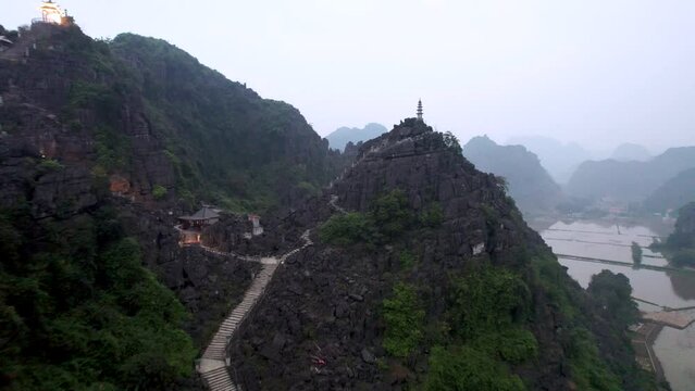 Vue a&eacute;rienne de Hang Mua &agrave; Ninh Binh au Vietnam, paysage karstique avec grotte, escalier et pagode sur la montagne du dragon couch&eacute;, culture et nature dans la baie d&rsquo;Halong terrestre.