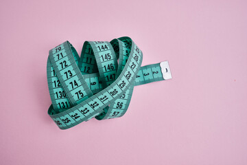 Green measuring tape on a light background. Tool for measuring length and volume. Tape for...