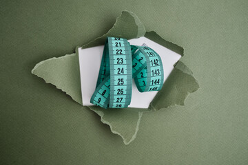 Green measuring tape on a light background. Tool for measuring length and volume. Tape for measuring in the clothing industry or the volume of the human body