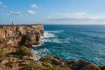 Farol de Sagres on the edge of the cliff washed by the big ocean waves. The lighthouse in Sagres Fortress, Portugal