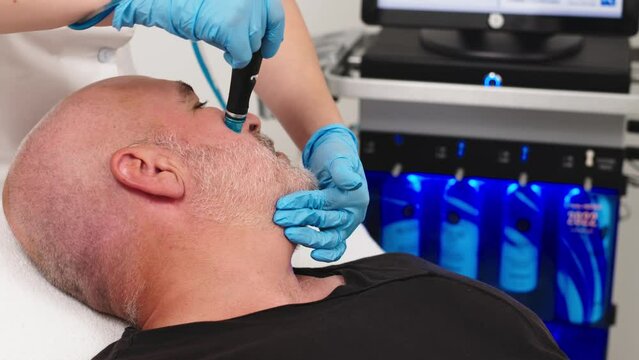 Middle aged male client during deep facial cleansing in a cosmetology clinic