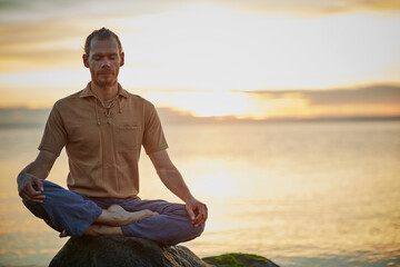 Go deep and then let it go. Shot of a man sitting in the lotus position during his yoga routine at...