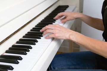 Close-up of female hands on piano keys. A woman with French manicure plays the piano. Musician with musical instrument learning music.
