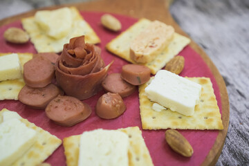 Cheese, Crackers, Sausage, and Almond nuts platter. Cheese plater on wooden plate for breakfast and snacking.