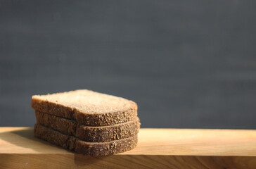 Rye bread cut into slices lies on a wooden table, gray background. Empty space for an inscription.