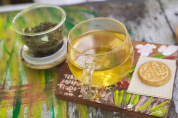 A glass of hot tea with biscuit in the morning with bokeh vintage garden backgrounds. Concept for Herbal drinks, Alternative medicine, Healthy food, Relaxation, Leisure activity.