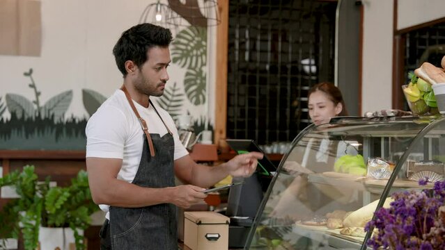 Indian man owns family's small coffee shop, helping wife count stock of confectionery in cabinet. to match computer screen And prepare to open cafe in morning every day. ready to receive customers.