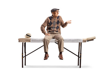 Elderly man sitting at a physical therapy bed and gesturing with hand
